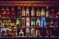 An array of various liquor bottles beautifully displayed on a bar shelf.